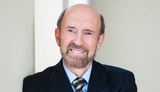 Head shot of David Marshall wearing navy blue suit with light blue shirt and gray and gold striped tie