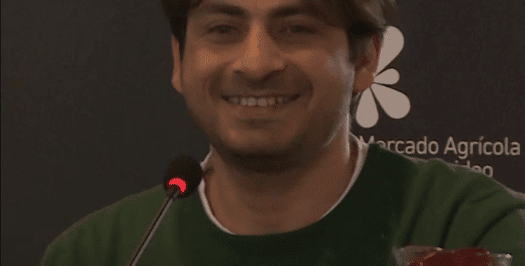 Ahmed Ajam wearing a green shirt speaking into a microphone