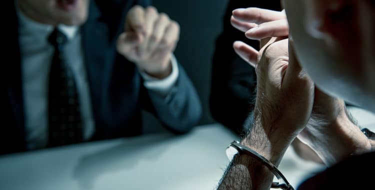 Man in handcuffs being interviewed by police