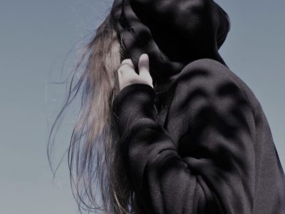 Young girl in black hoodie pulling hood over her head