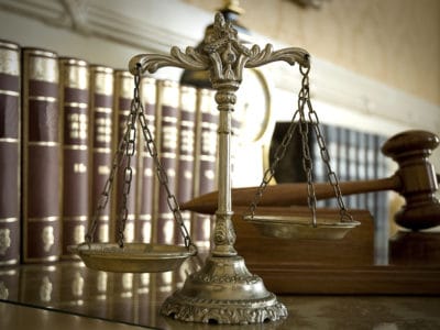 Scales of Justice and Judge's gavel with rows of books in background