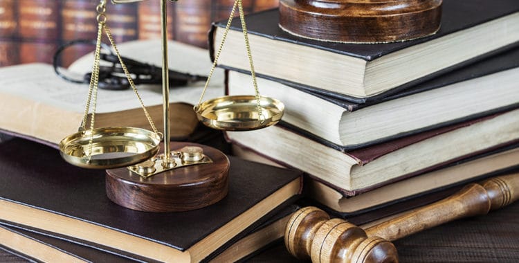 Wood gavel, bunch of keys, scales and stack of old books against the background of a row of antique books bound in leather