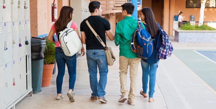 group of male and female students walking down a high school hallway