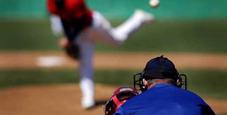 Blurred baseball player throwing ball with umpire and catcher in foreground