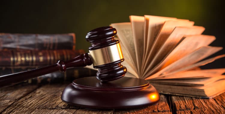 Judge's gavel on a wooden desk, law books in background