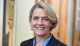 Head shot of Kristina Selset wearing navy blue suit in The Marshall Defense Firm office