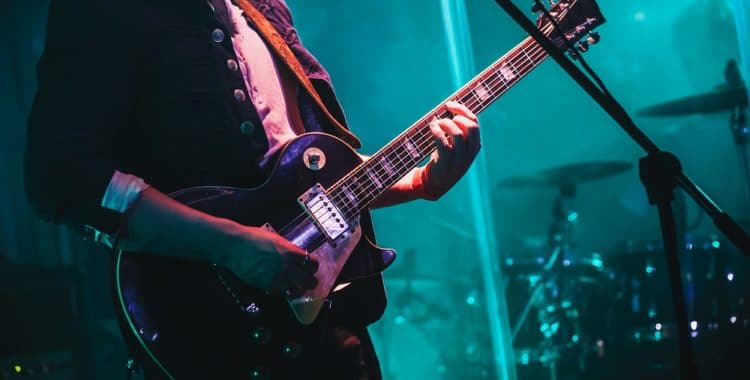 Man playing electric guitar with blue background